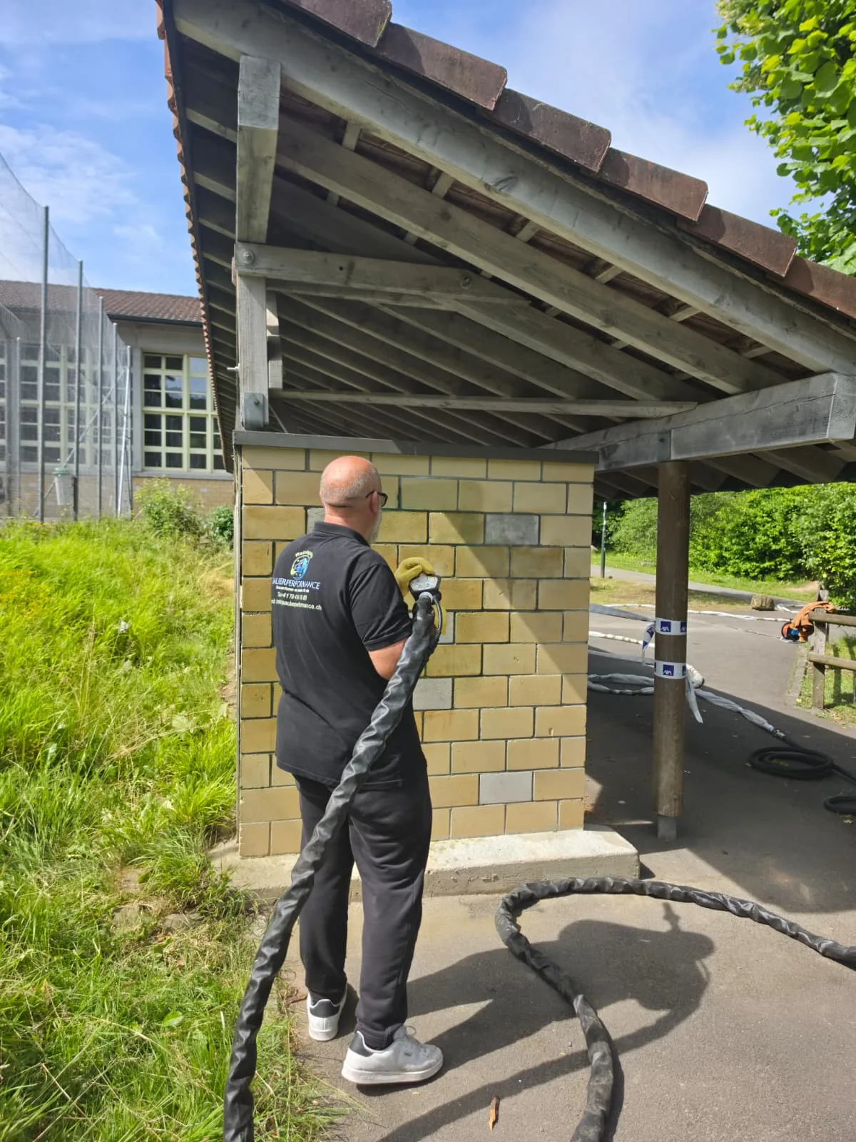 Sauberperformance Mitarbeiter bei der Arbeit an einer Backsteinwand